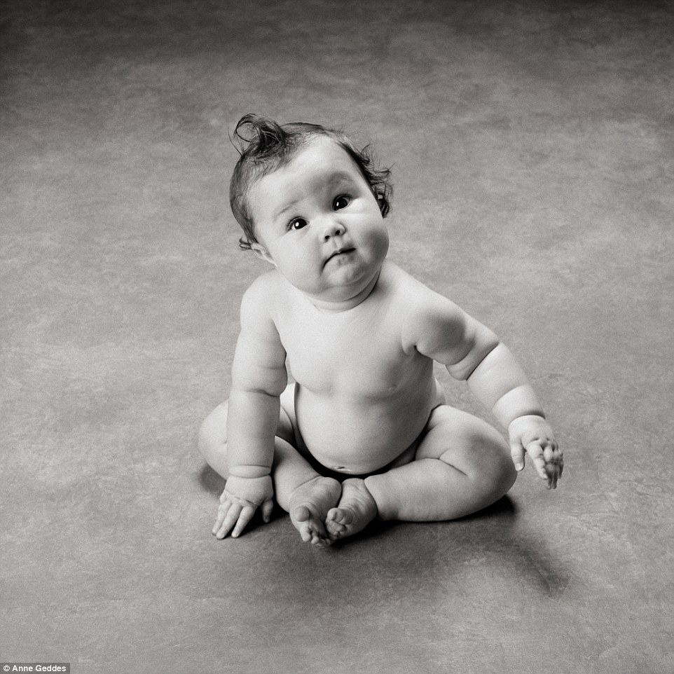 A chubby little baby looks perplexed as she sits on the floor in this black and white shot by the iconic snapper