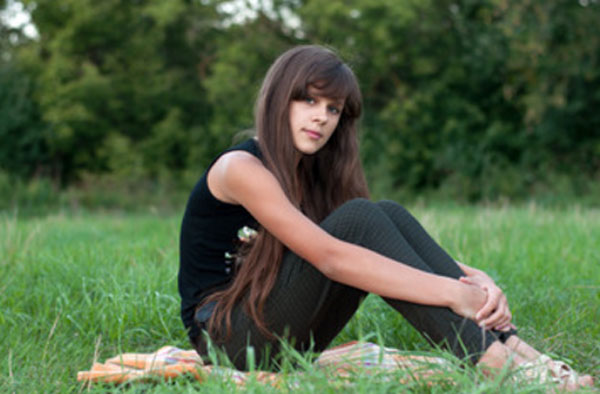 Девочка - подросток сидит на траве